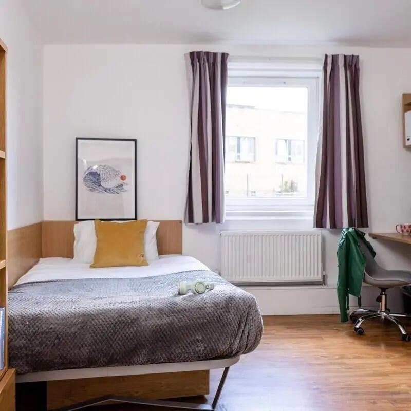Bed with yellow cushion and artwork Bedroom at Cranborne House in Bournemouth Student Accommodation