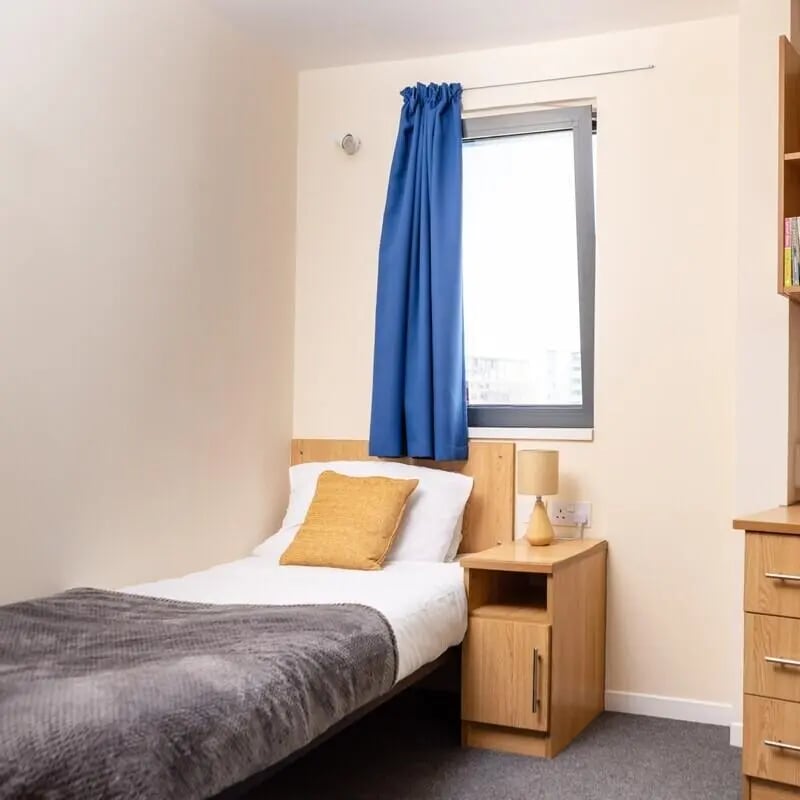 Bed grey blanket yellow pillow bedside table bedroom at Chesil House in Bournemouth Student Accommodation