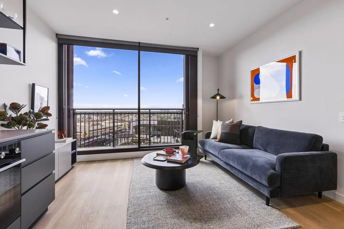 Blue couch coffee table artwork large window living room at Indi Footscray in Melbourne Student Accommodation