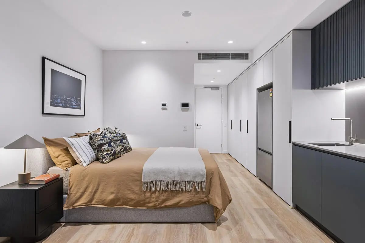Bed with artwork modern kitchen built in storage Bedroom kitchen at Indi Footscray in Melbourne Student Accommodation