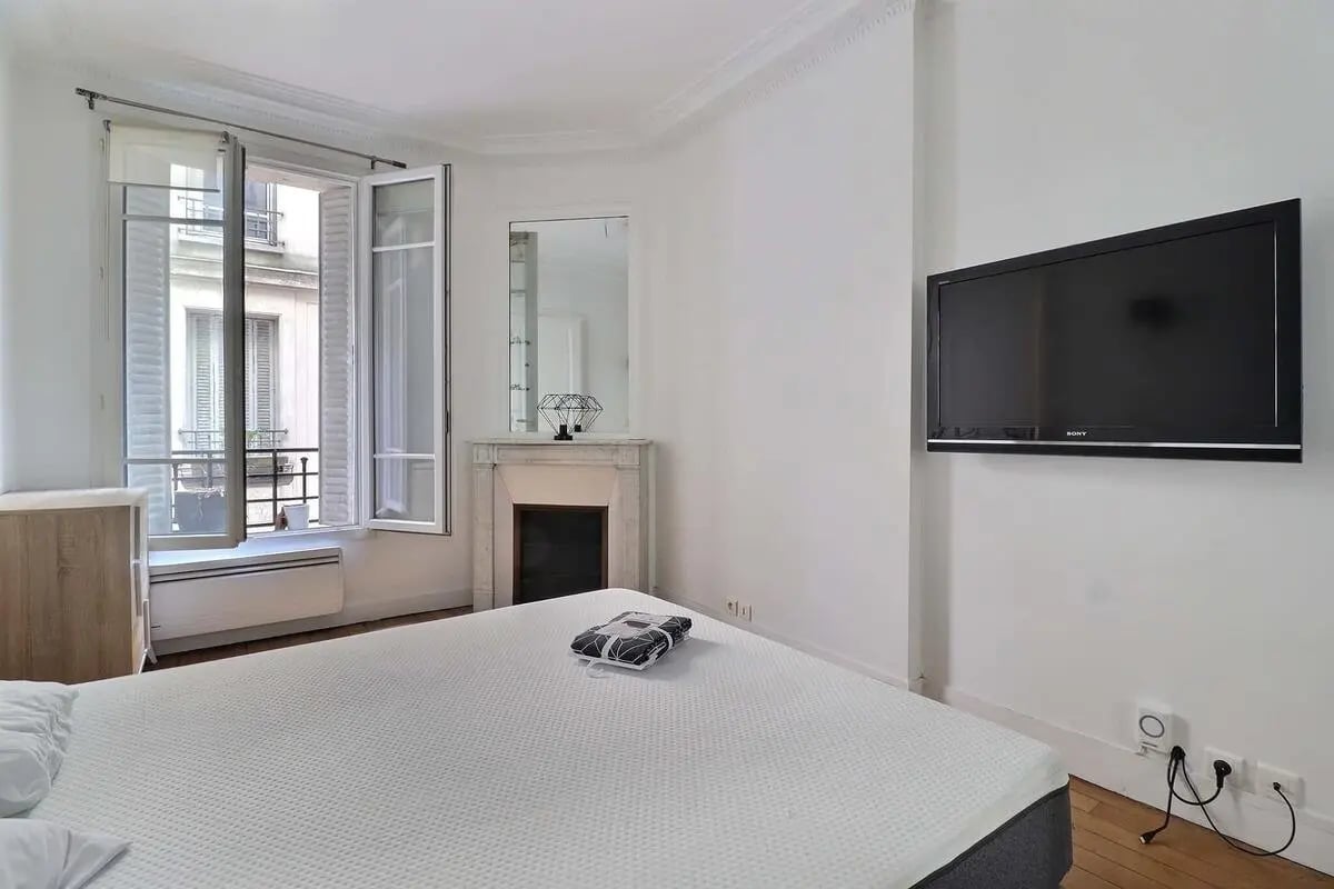 Bed fireplace TV window bedroom at Apartment in Rue Etienne Jodelle, 75018 Paris, France in Paris Student Accommodation