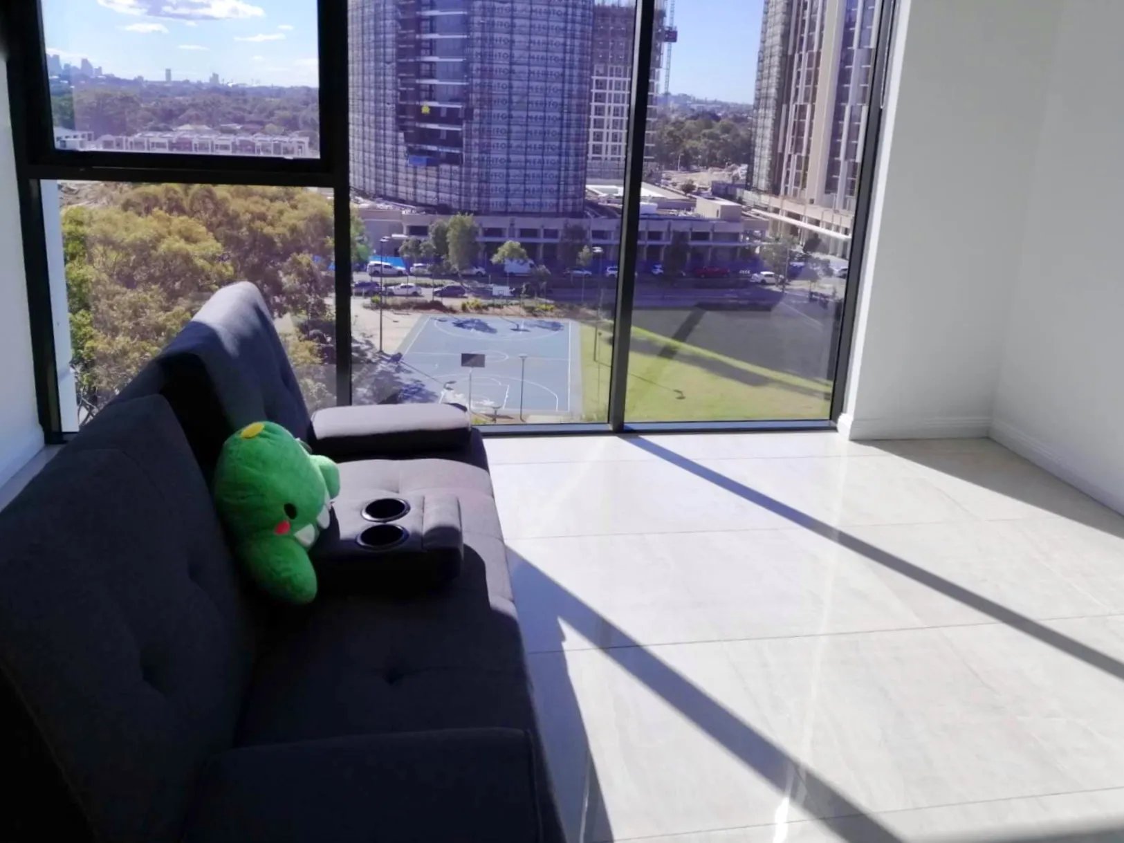 Dark sofa with plush toy and city view living room at Belong Eastgardens in Sydney Student Accommodation