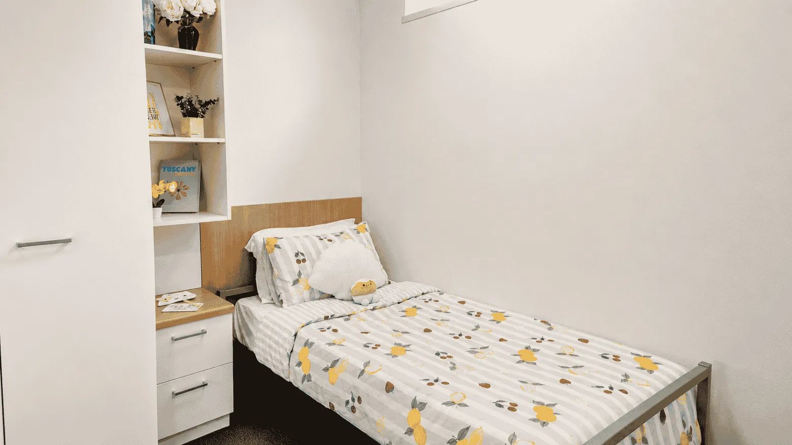 Bed with lemon print bedding bookshelf and drawers bedroom at UniLodge @ Metro Adelaide in Adelaide Student Accommodation