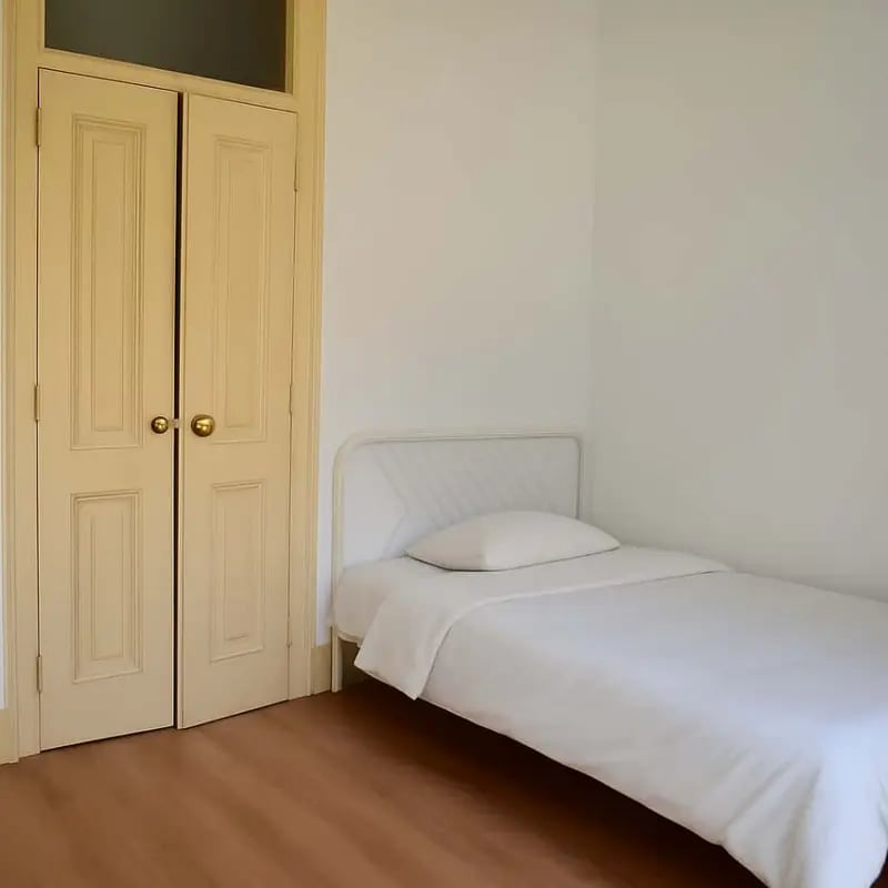 Single bed with white bedding and doors bedroom at Quarto com cama de casal em apartamento com 8 quartos - FLAT G - G08 in Lisbon Student Accommodation