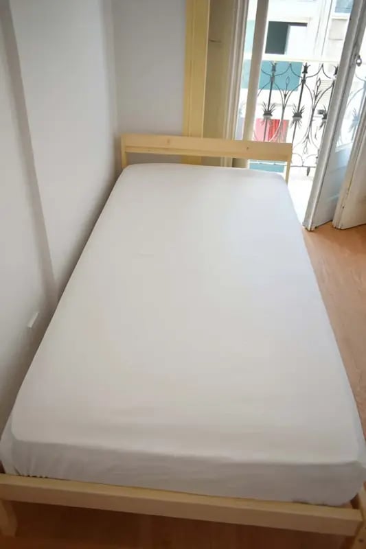 Wooden bed frame with white fitted sheet bedroom at Quarto com cama de casal em apartamento com 8 quartos - FLAT G - G08 in Lisbon Student Accommodation