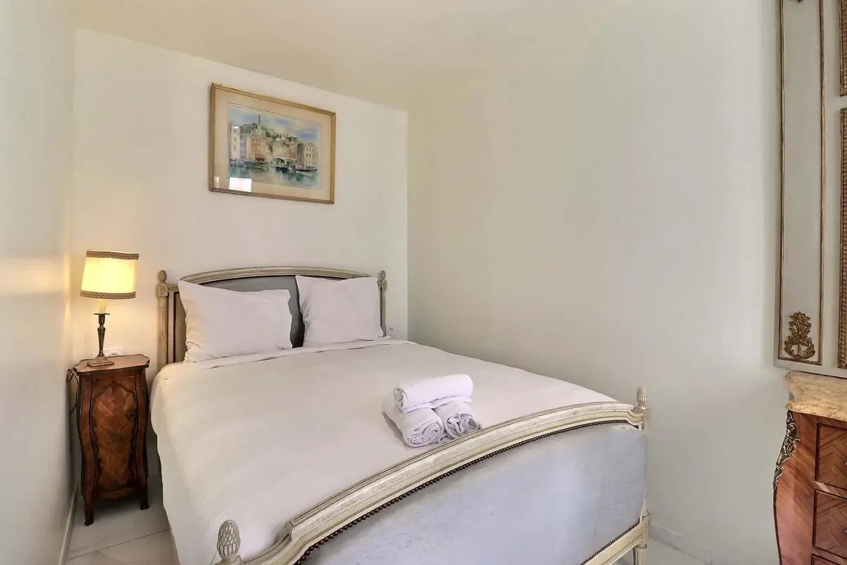 Bed with white linens nightstand lamp painting bedroom at Apartment in Rue Sedaine, Paris for 37 m² with 1 bedroom in Paris Student Accommodation