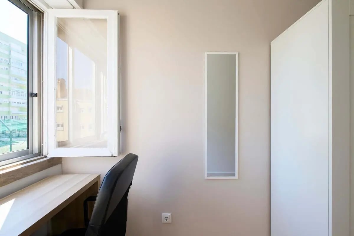 Desk chair open window mirror wardrobe bedroom at Bedroom in a 10-Bedroom Apartment in Avenida Estados Unidos da América, Lisbon - Room 1 in Lisbon Student Accommodation