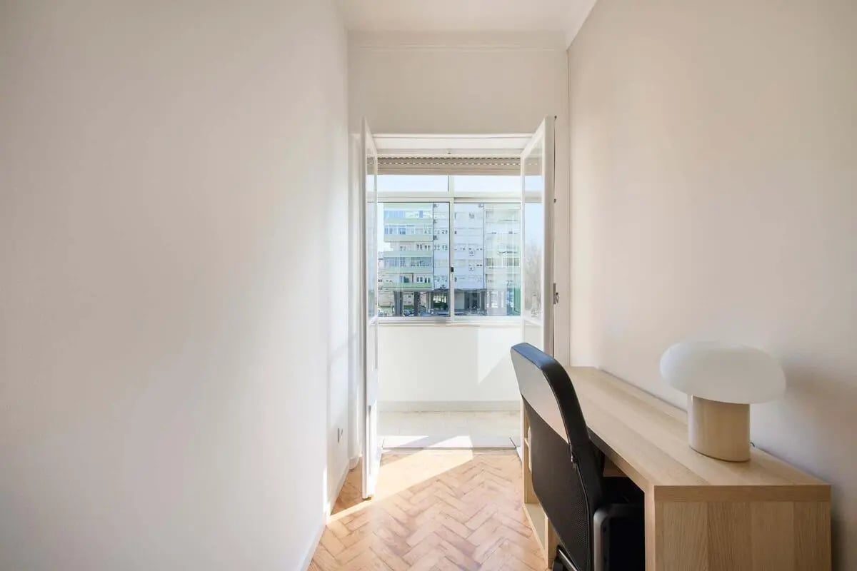 Desk chair lamp and balcony view study area at Bedroom in a 10-Bedroom Apartment in Avenida Estados Unidos da América, Lisbon - Room 1 in Lisbon Student Accommodation