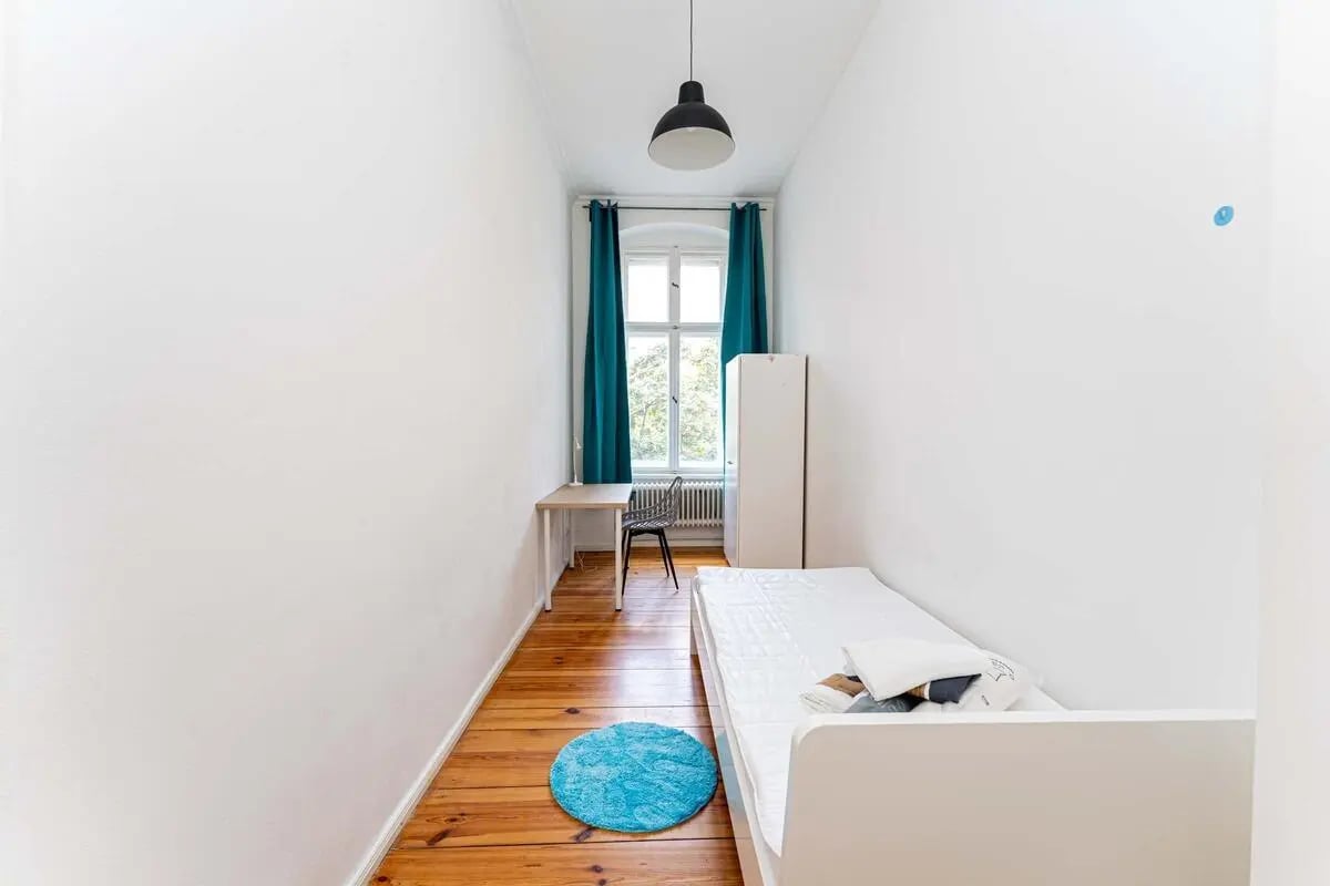 Bed desk chair closet blue rug bedroom at Kaiser-Friedrich-Straße - Room 4 in Berlin Student Accommodation