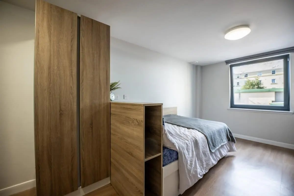 Wooden wardrobe bed with grey blanket window bedroom at Haddington Place in Edinburgh Student Accommodation