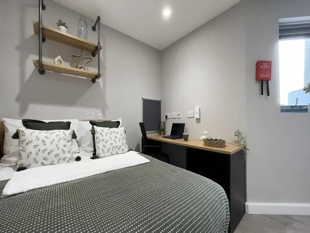 Bed desk shelves pillows and a laptop bedroom at The Coal Yard in York Student Accommodation