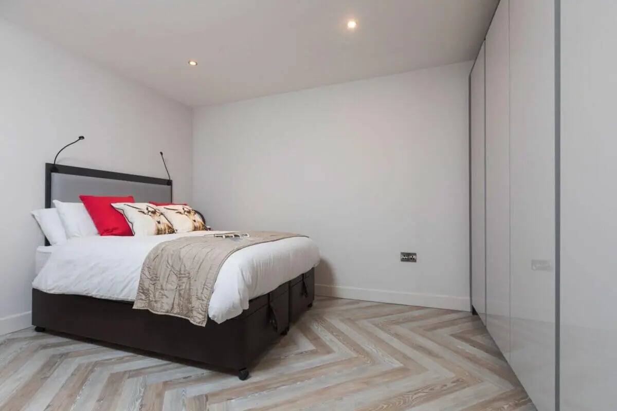 Bed with red pillows and modern wardrobe bedroom at dwell 121 Princess Street in Manchester Student Accommodation