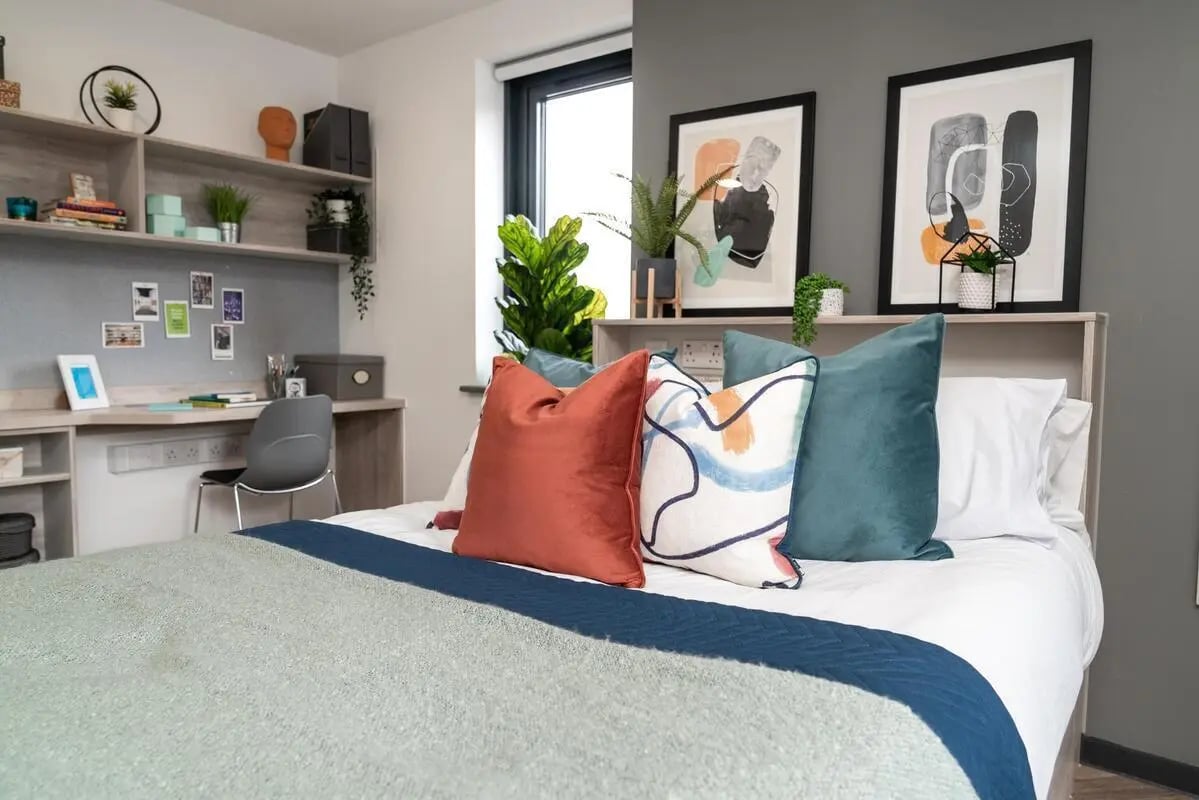 Bed with colorful pillows study desk artwork bedroom at Steelworks in Sheffield Student Accommodation