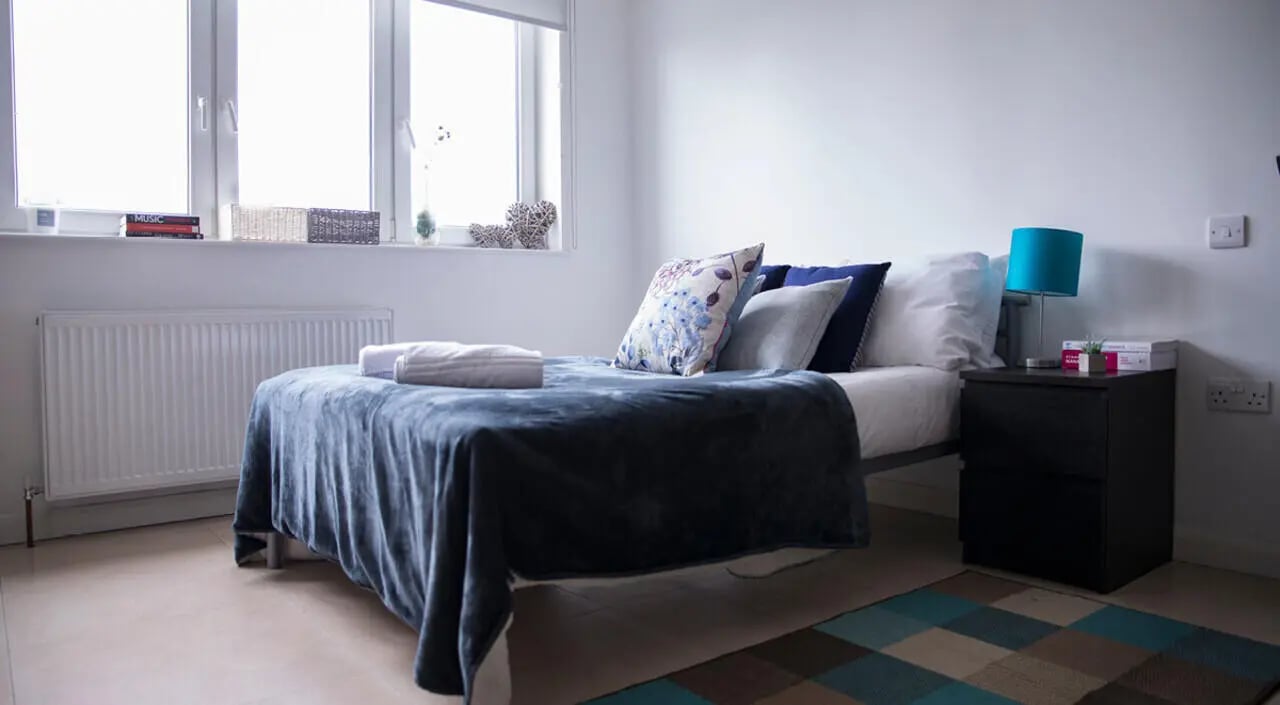 Bed pillows radiator bedside table lamp bedroom at Portobello Garrow House in London Student Accommodation