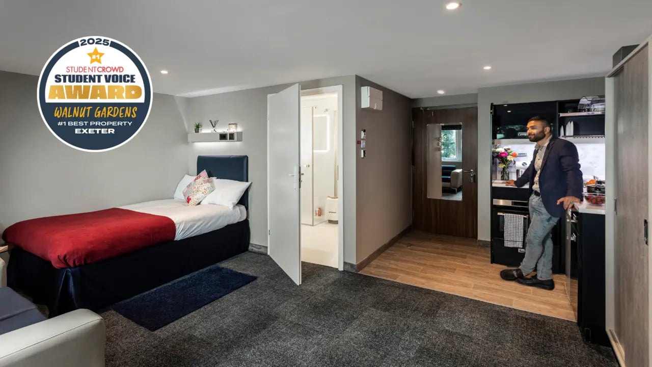 Bed with red throw and kitchen area. at Study Inn Walnut Gardens Exeter in Exeter Student Accommodation