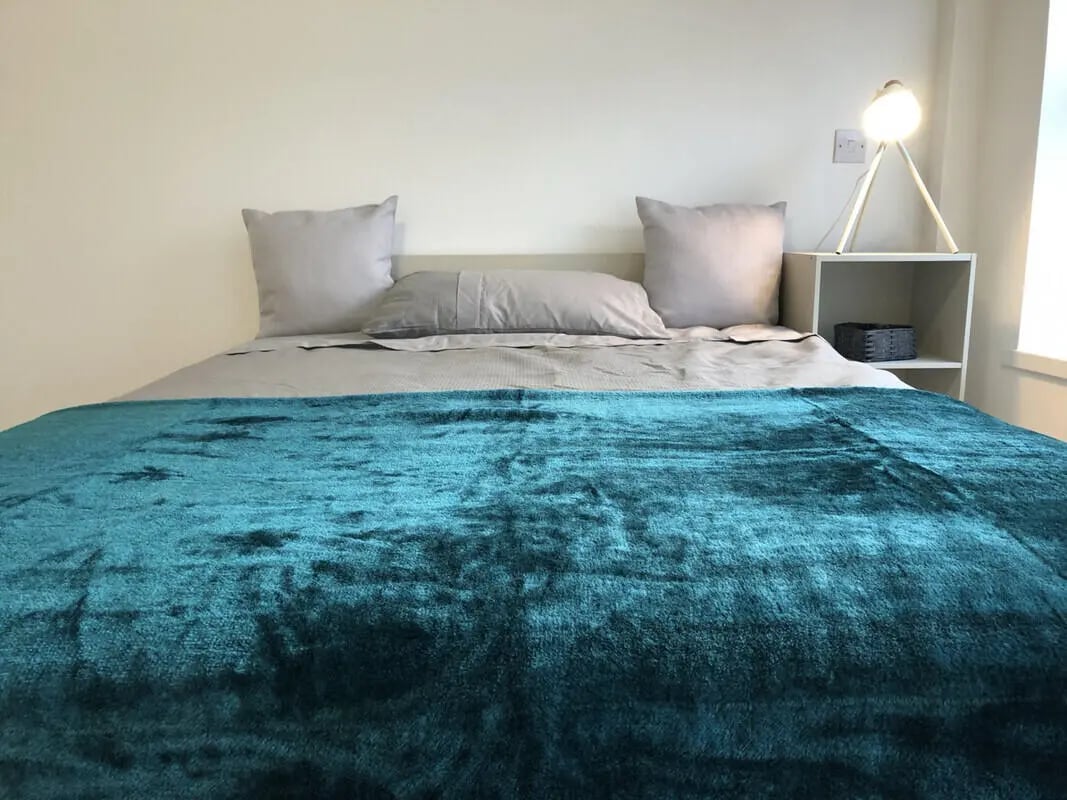 Bed with teal throw pillows and lamp bedroom at Metchley Hall in Birmingham Student Accommodation