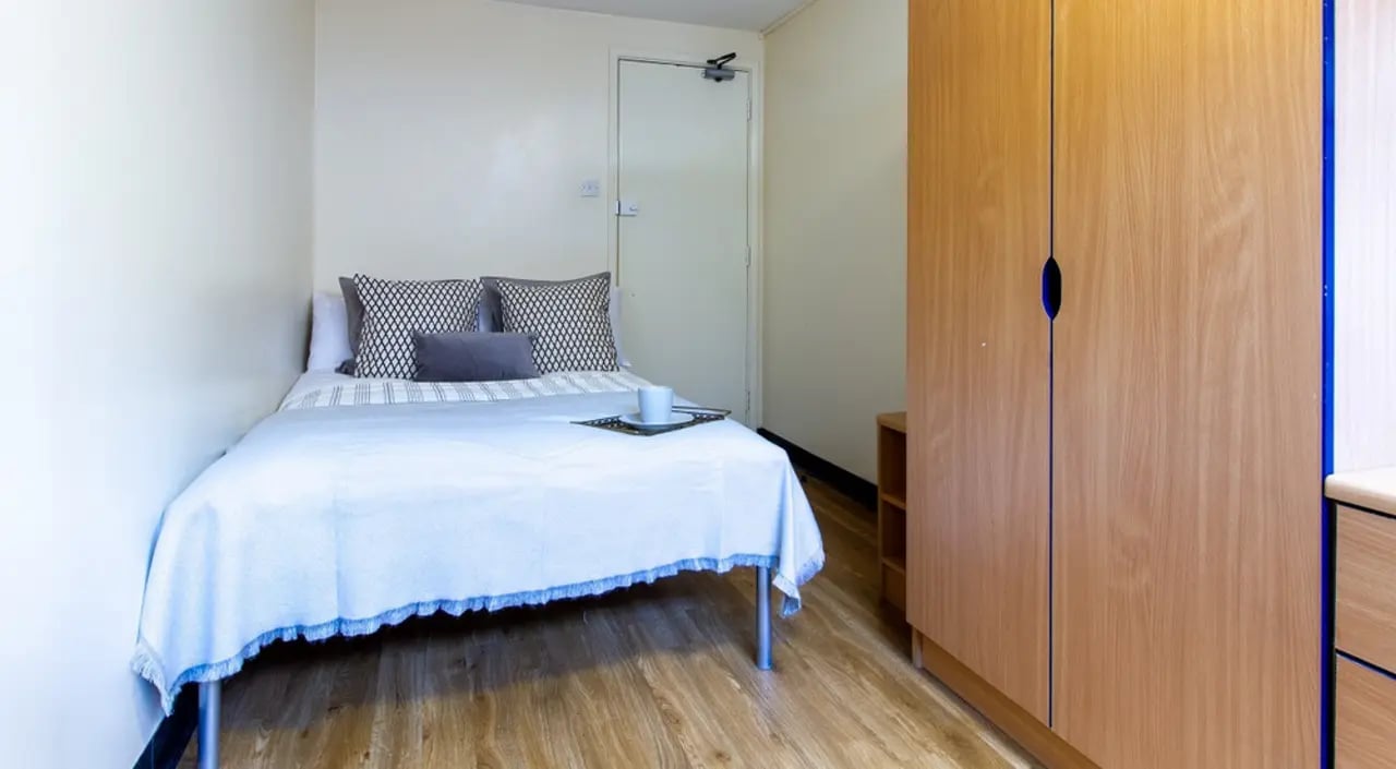 Bed with patterned pillows wardrobe and tray bedroom at Ben Russell Court in Leicester Student Accommodation