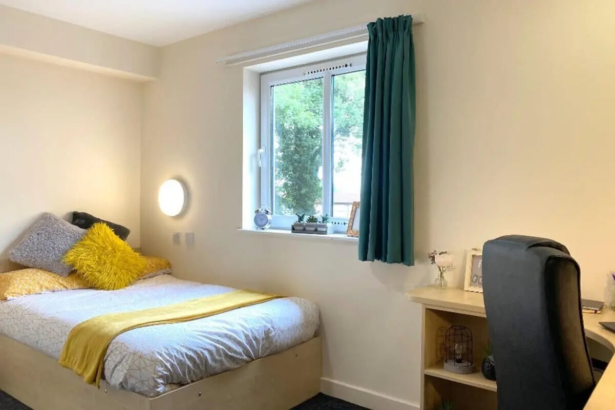 Bed with yellow blanket and pillows desk chair Image Type Bedroom at The Cube - Loughborough in Loughborough Student Accommodation