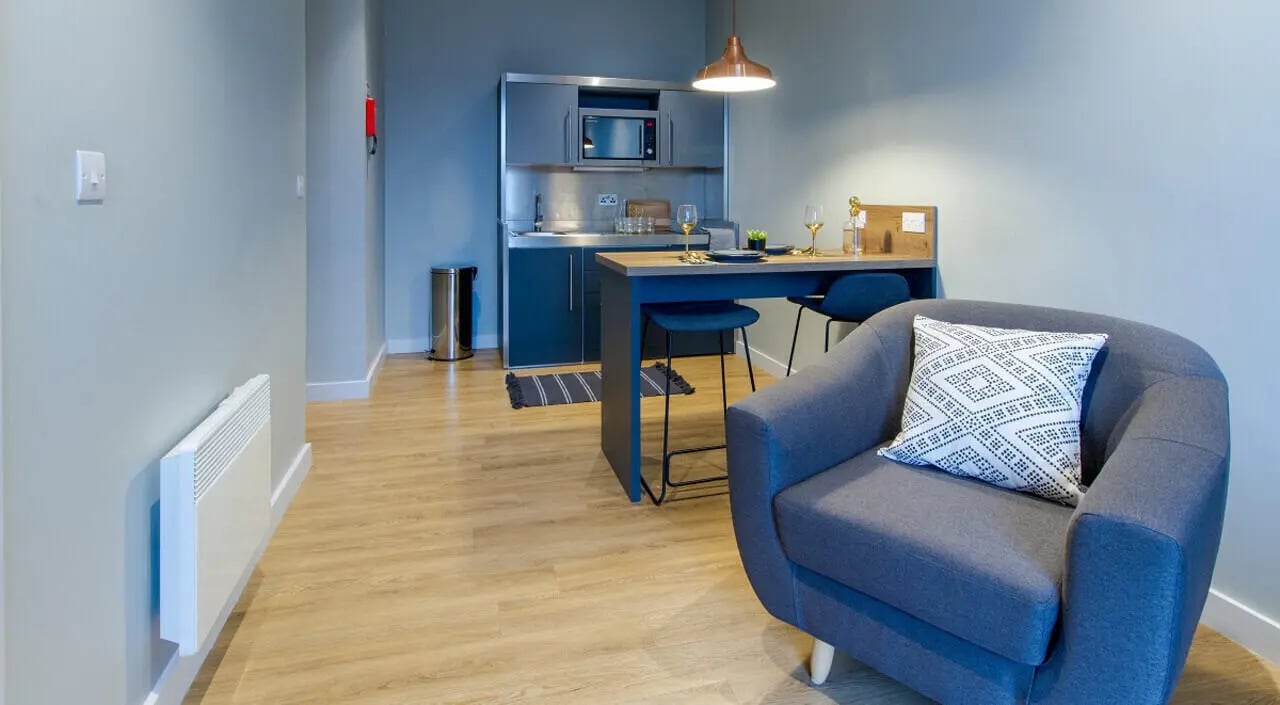 Gray armchair kitchen counter bar stools living room at Crown House in Sheffield Student Accommodation