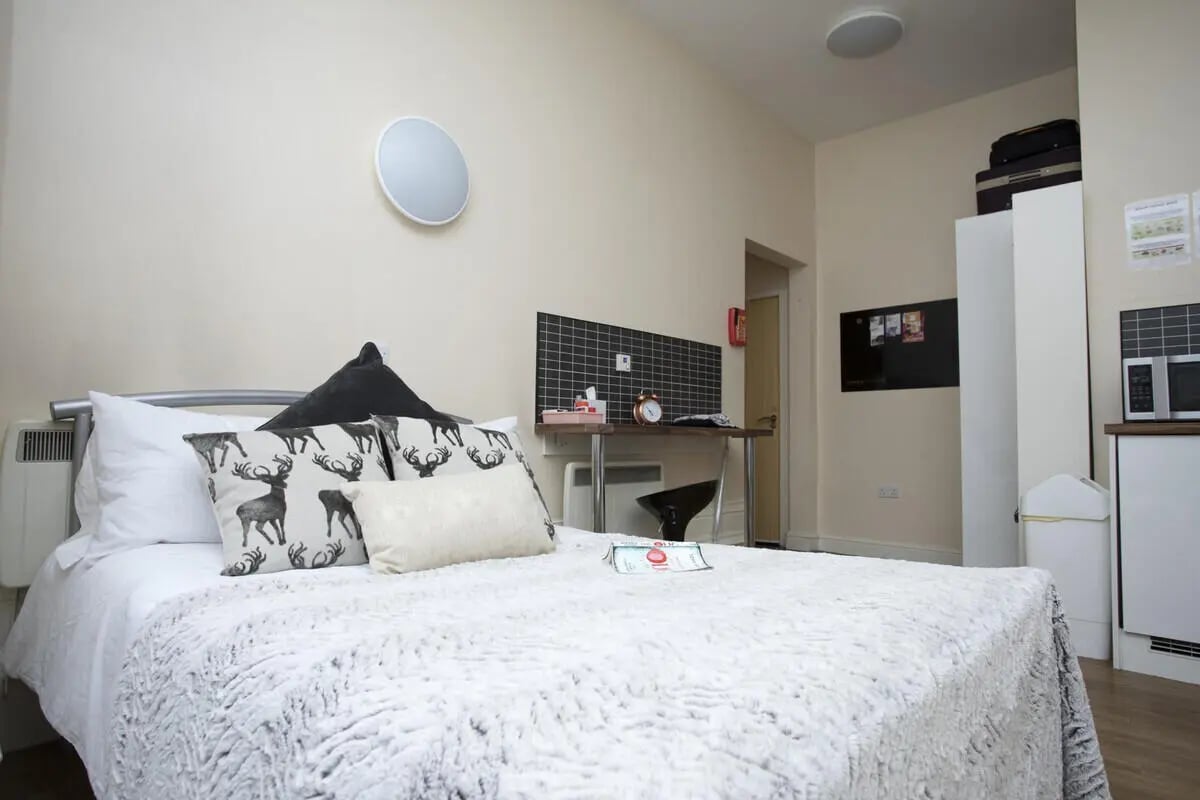 Bed with deer pillows and desk area bedroom at Daisybank Villas in Manchester Student Accommodation
