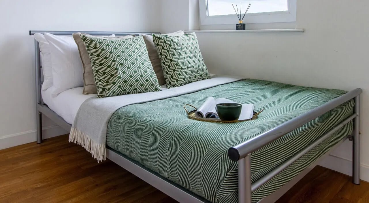 Metal bed with green patterned duvet and pillows bedroom at Canalside in Birmingham Student Accommodation