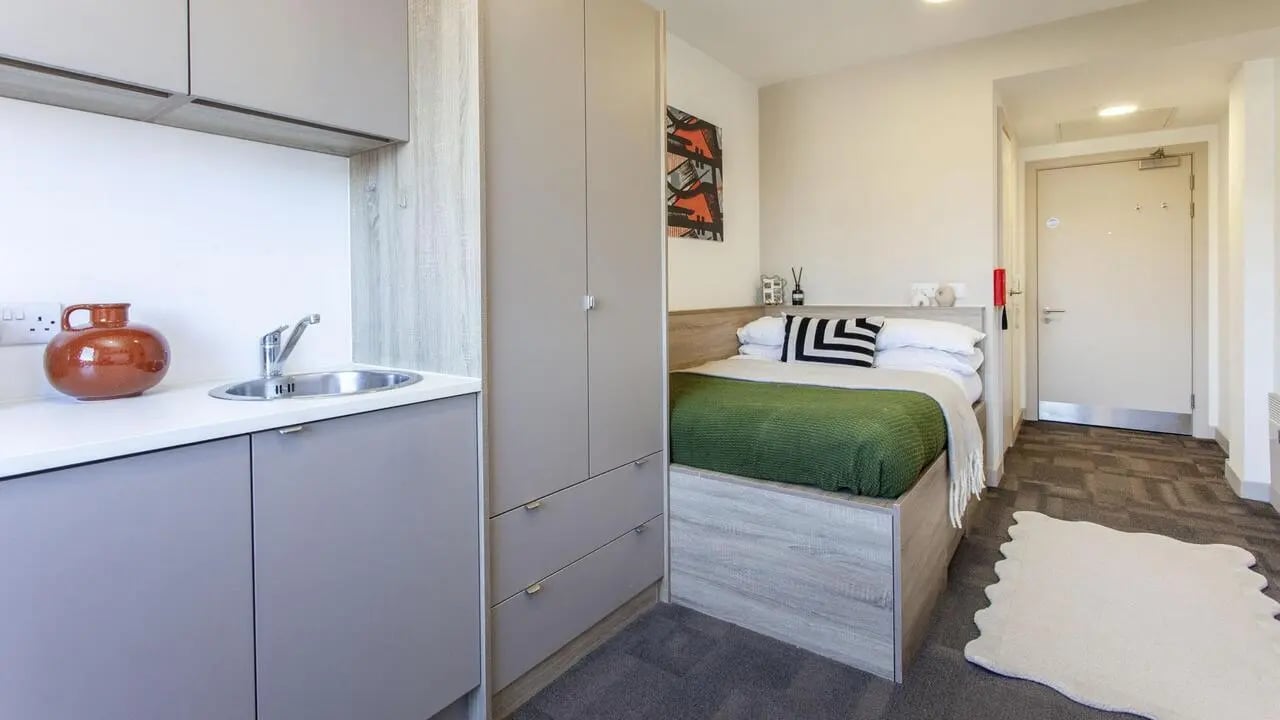 Bed with green throw sink and wardrobe studio apartment at Berkshire House Reading in Reading Student Accommodation