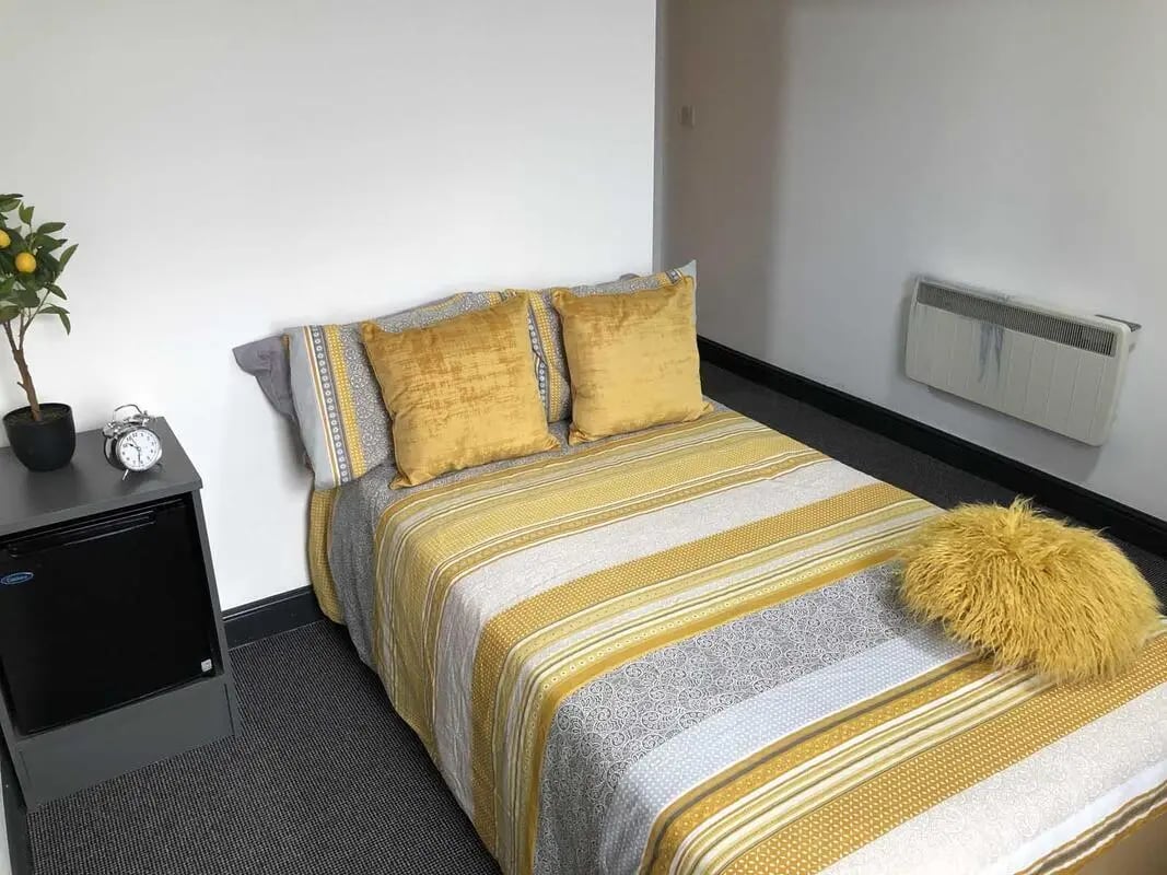 Bed with yellow pillows and bedside table Bedroom at Mandale Terrace in Stockton-On-Tees Student Accommodation