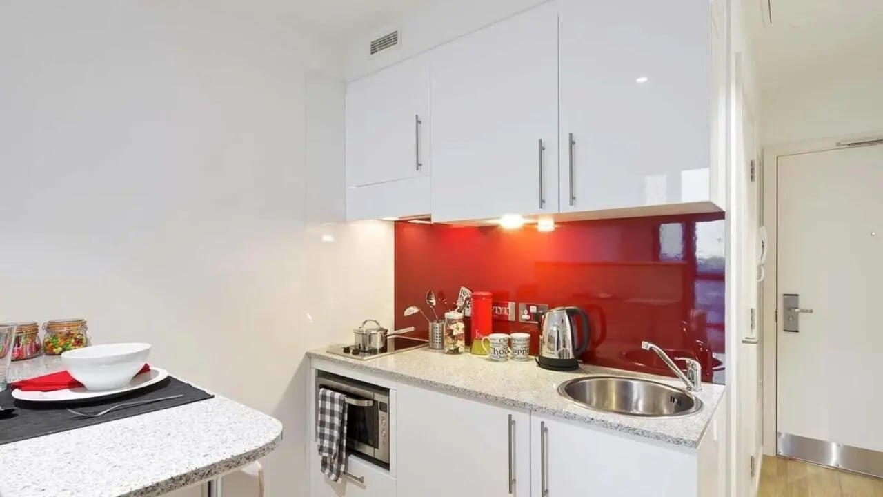 White cabinets microwave kettle sink red backsplash kitchen at Wood Lane Studios in London Student Accommodation