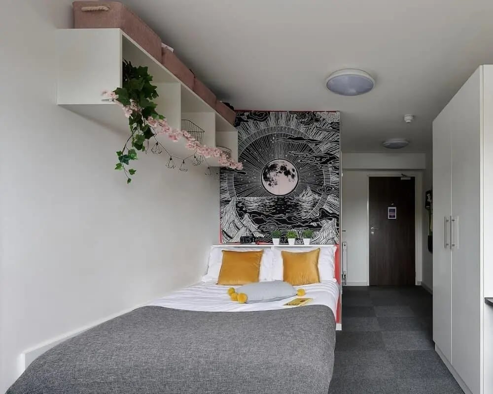 Bed with yellow pillows and grey blanket bedroom at Frobisher House in Plymouth Student Accommodation