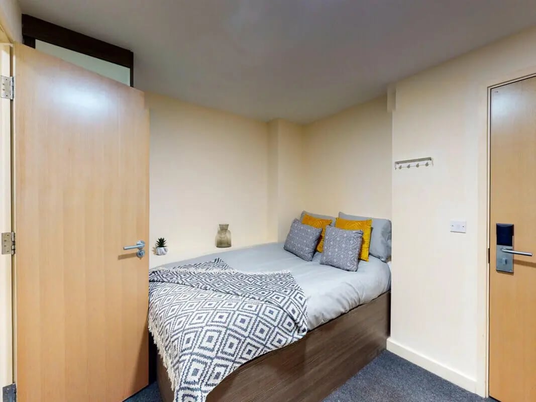 Bed with pillows blanket and plant bedroom at The Cube in Bolton Student Accommodation