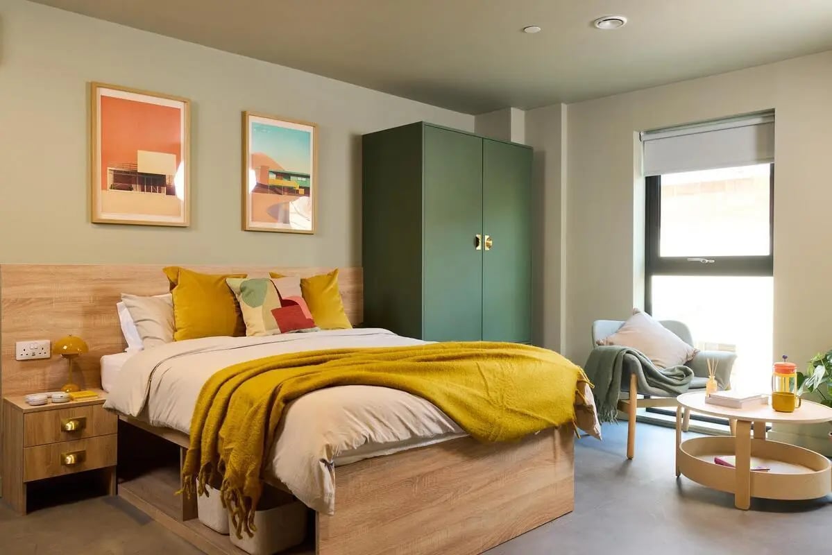 Bed nightstand artwork green wardrobe armchair coffee table bedroom at The Store House in Leeds Student Accommodation