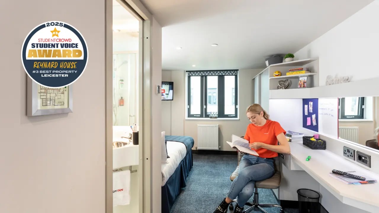Student reads at desk next to bed living area at Reynard House in Leicester Student Accommodation