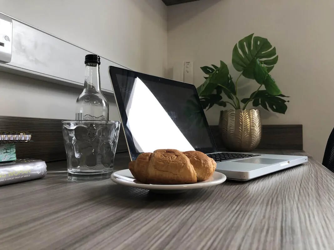 Laptop croissants glass bottle plant study area at Q Studios in Stoke-On-Trent Student Accommodation
