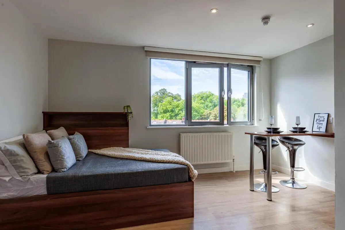 Bed with pillows and bar stools with table bedroom at Central Studios - London in London Student Accommodation