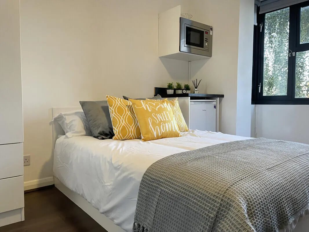 Bed with yellow sweet home pillows fridge microwave bedroom at Hockley Point in Nottingham Student Accommodation