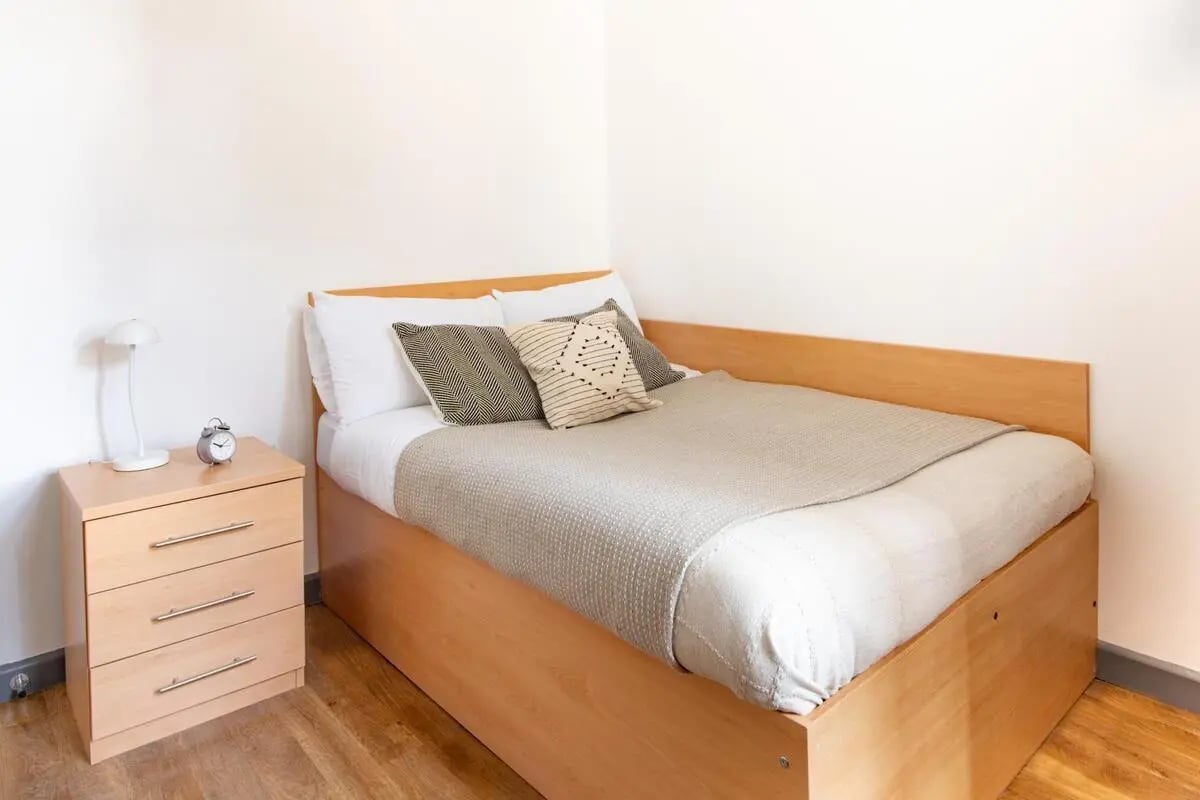 Bed with bedside table lamp alarm clock and pillows Bedroom at Alexandra Hall in Aberystwyth Student Accommodation