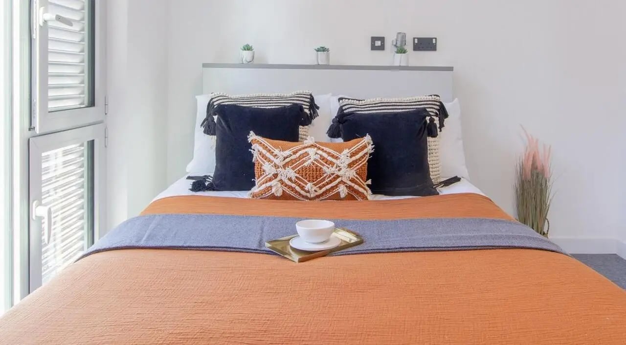 Orange bed with decorative pillows and tray bedroom at The Union Leamington in Leamington Spa Student Accommodation