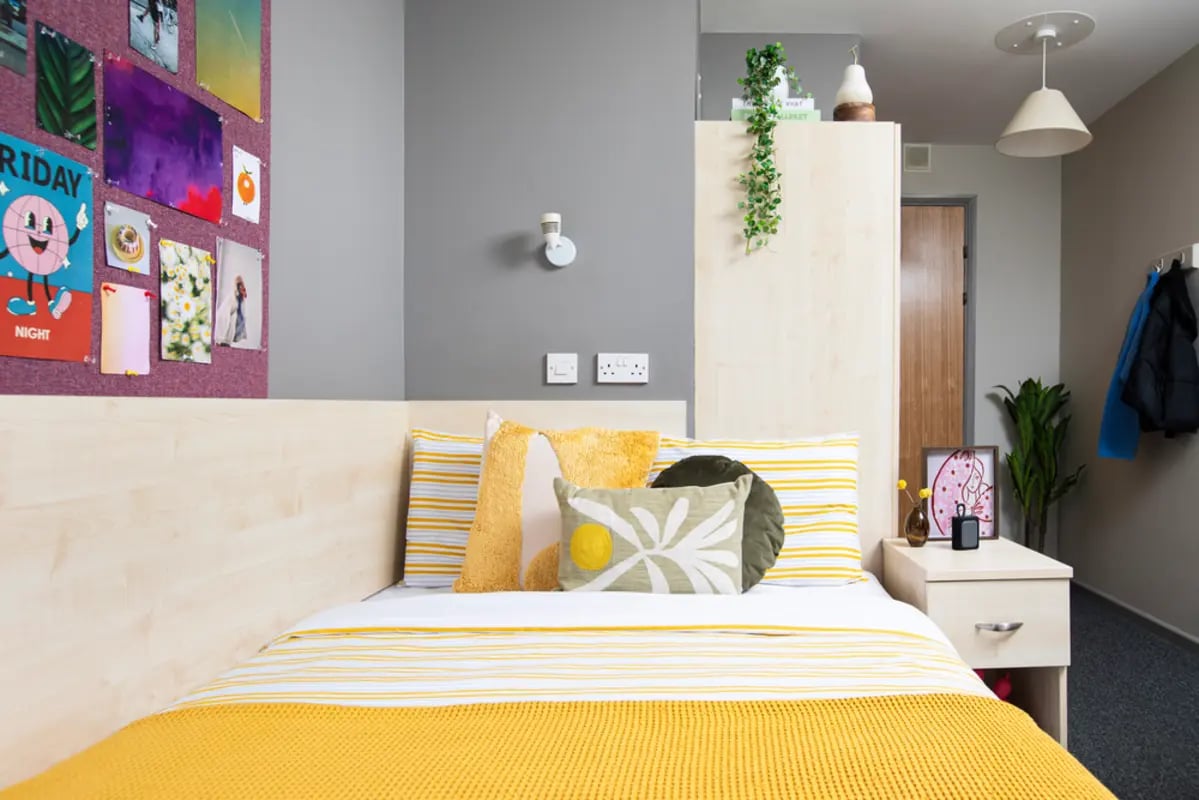 Bed with yellow bedding and decorative pillows bedroom at Newarke Point in Leicester Student Accommodation