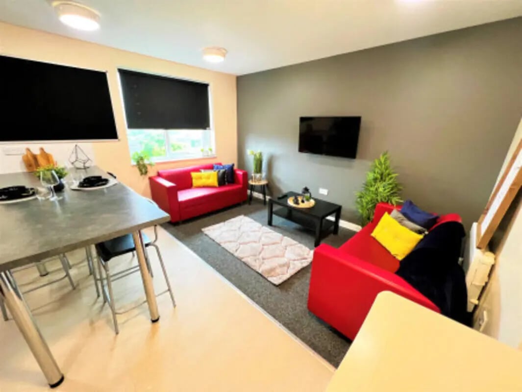 Red sofas coffee table rug living room at Jubilee Court in Preston Student Accommodation
