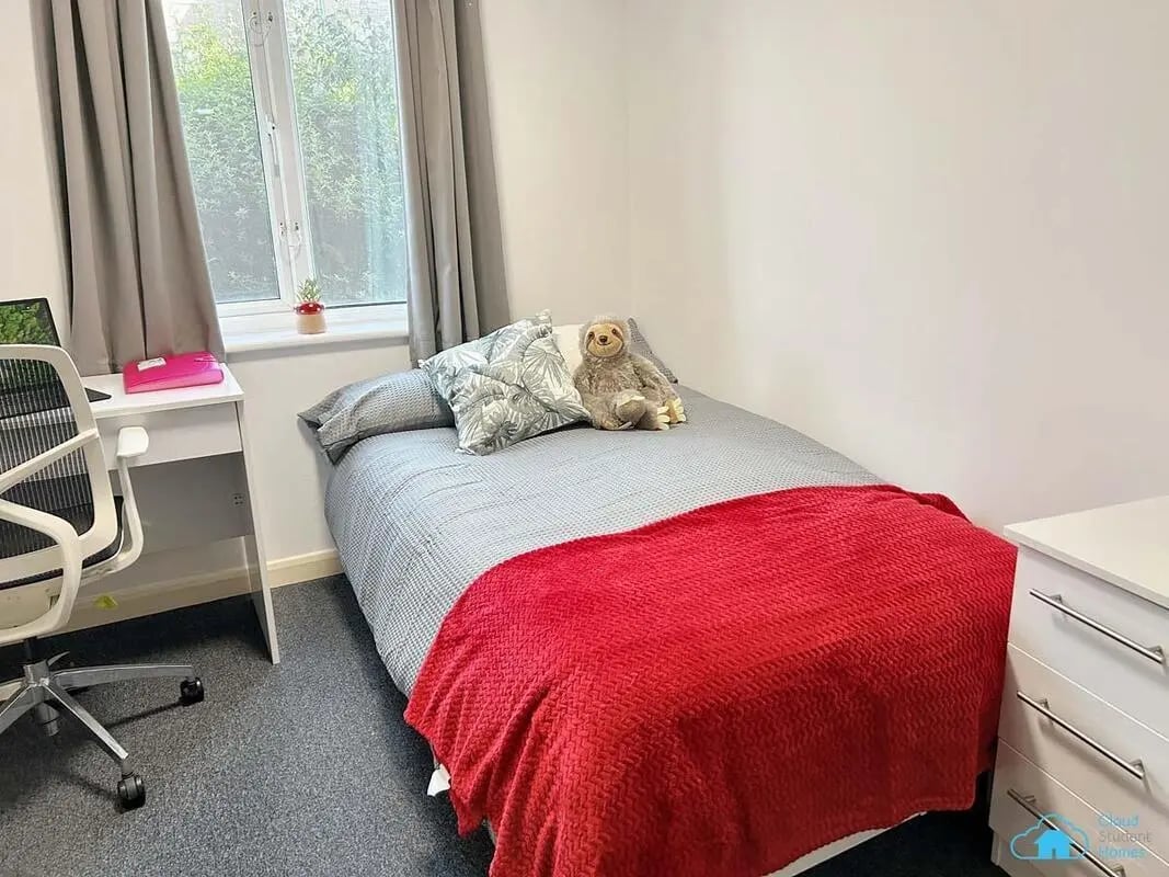 Bed with red blanket, sloth, desk, chair bedroom at Rochester Student Village in Rochester Student Accommodation