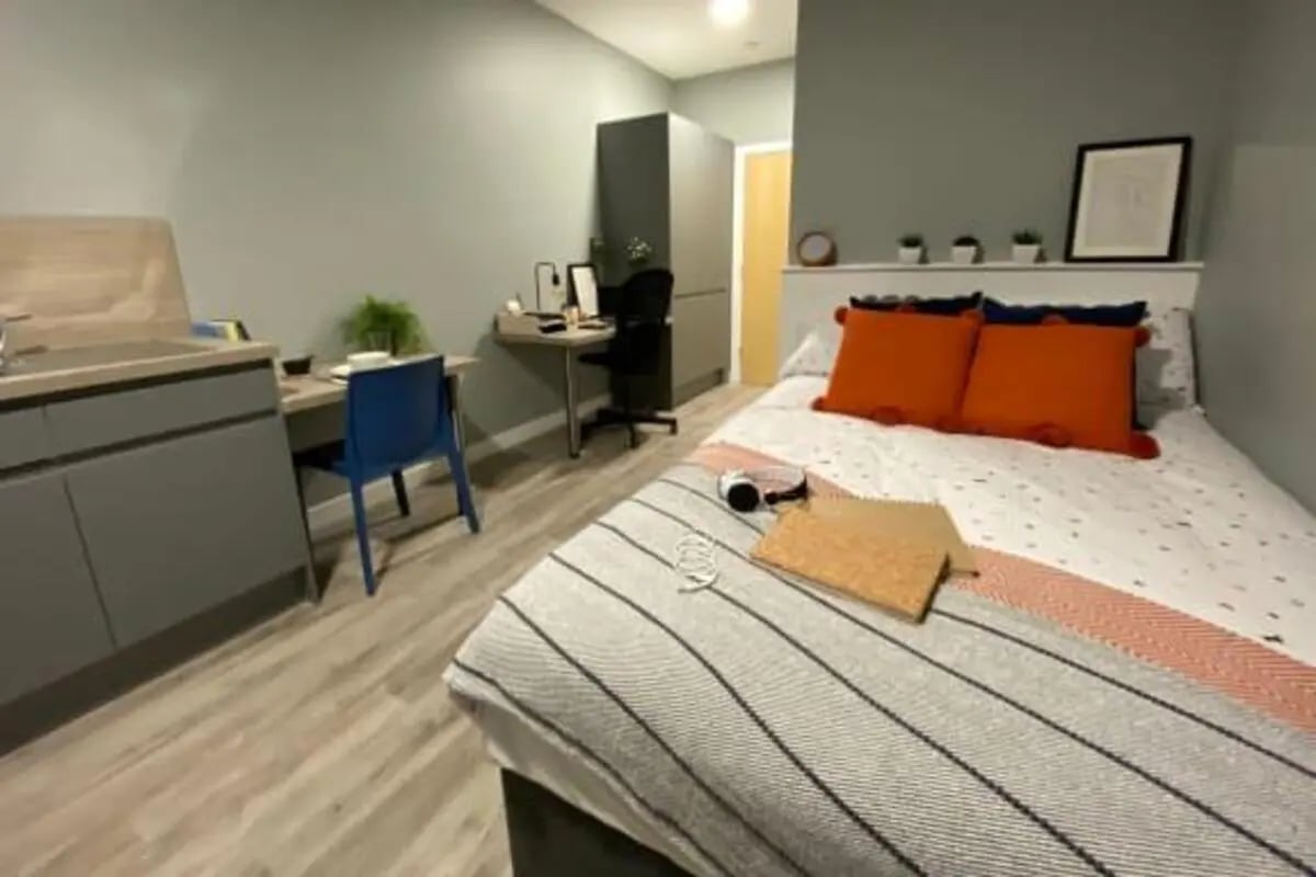 Bed with orange pillows and desk area bedroom at Luneside in Lancaster Student Accommodation