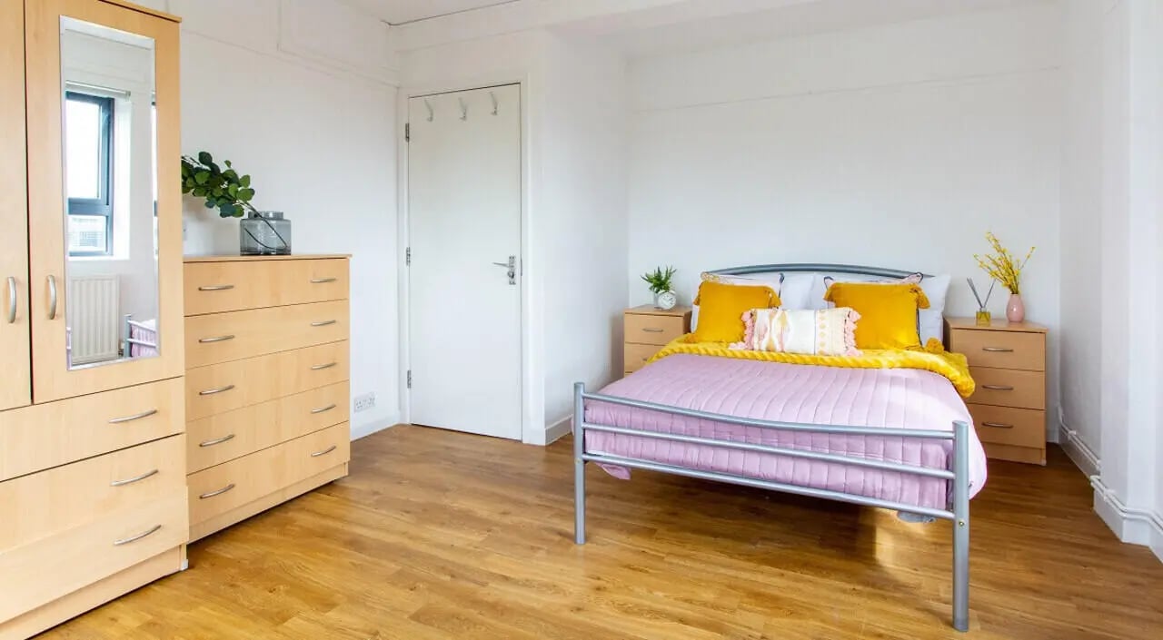 Wardrobe dresser bed with yellow pillows bedroom at Surrey Quays Landale House in London Student Accommodation