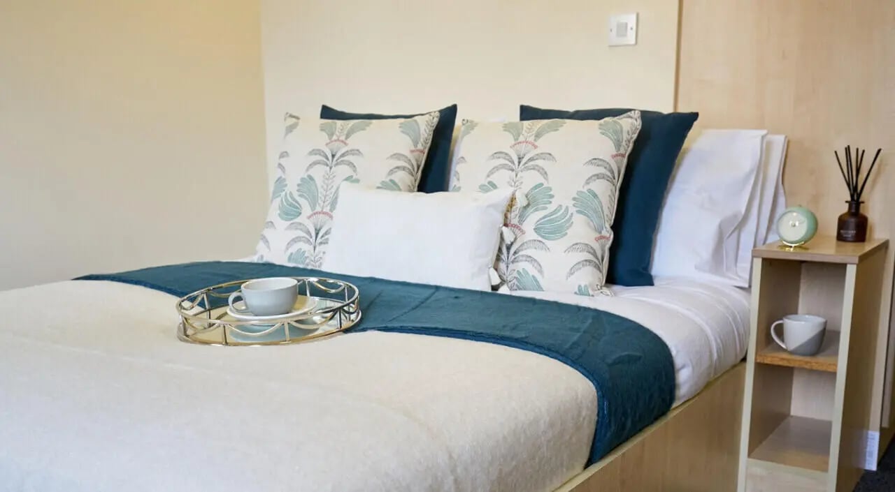 Bed with patterned pillows tray and bedside table bedroom at Trinity Student Village in Preston Student Accommodation