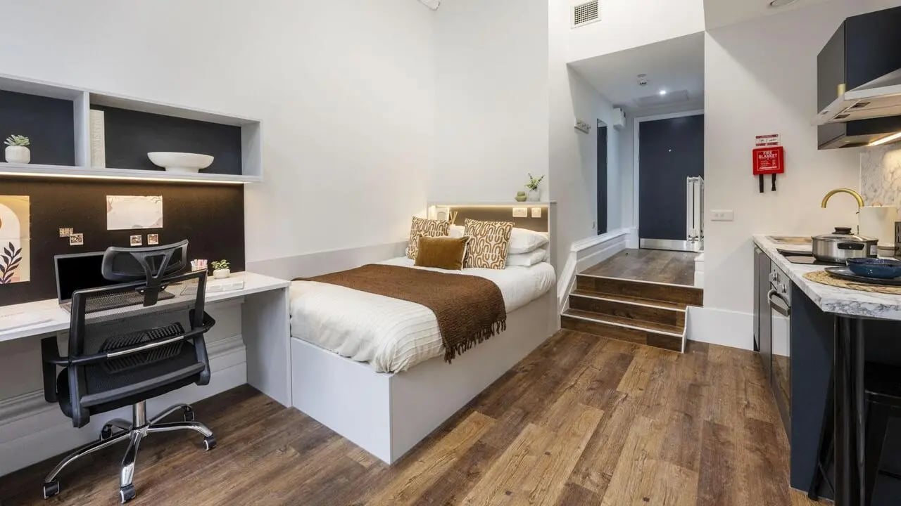 Desk bed kitchen area steps with door at 26 Great George Street in Leeds Student Accommodation