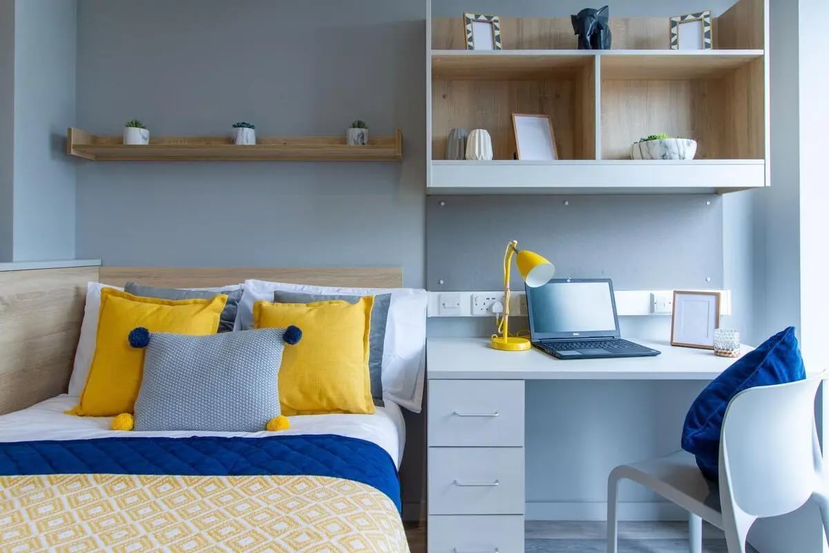 Bed with yellow pillows and desk bedroom at Renslade House in Exeter Student Accommodation
