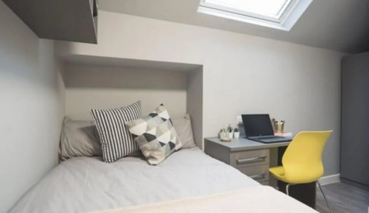 Bed desk with laptop yellow chair bedroom at Allen Court in Manchester Student Accommodation
