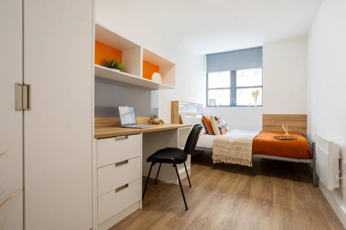 Desk laptop chair bed with orange bedding bedroom at Manchester Student Village in Manchester Student Accommodation