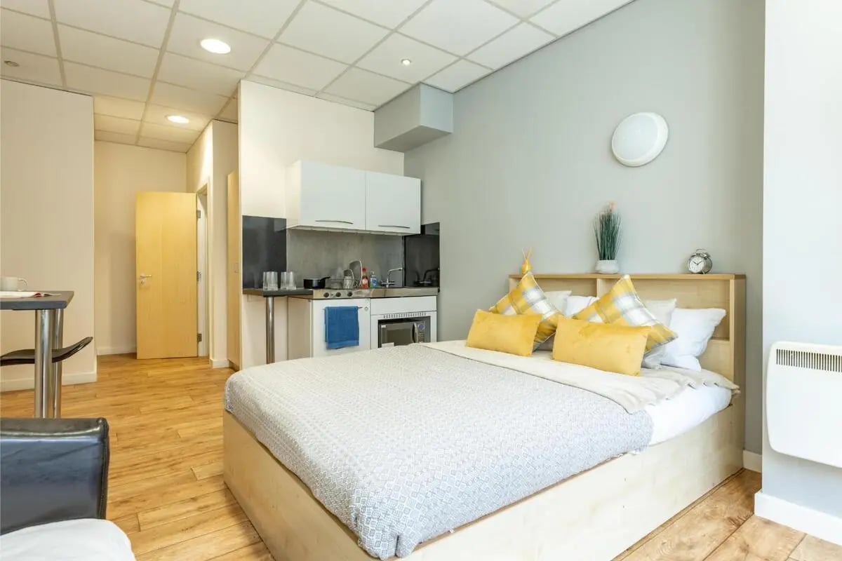 Bed kitchen cabinets stove oven and doorway studio apartment at Chambers 51 in Wolverhampton Student Accommodation