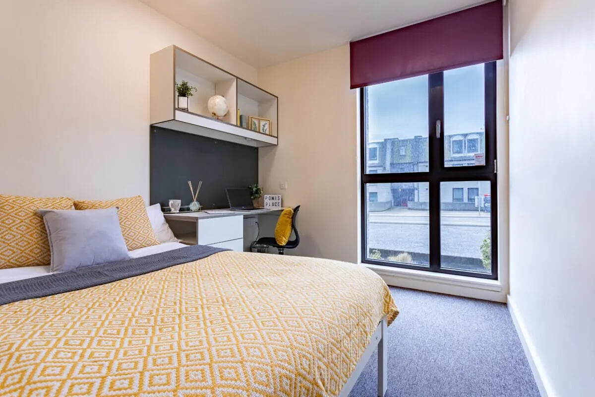 Bed with yellow blanket study desk and window bedroom at Powis Place in Aberdeen Student Accommodation