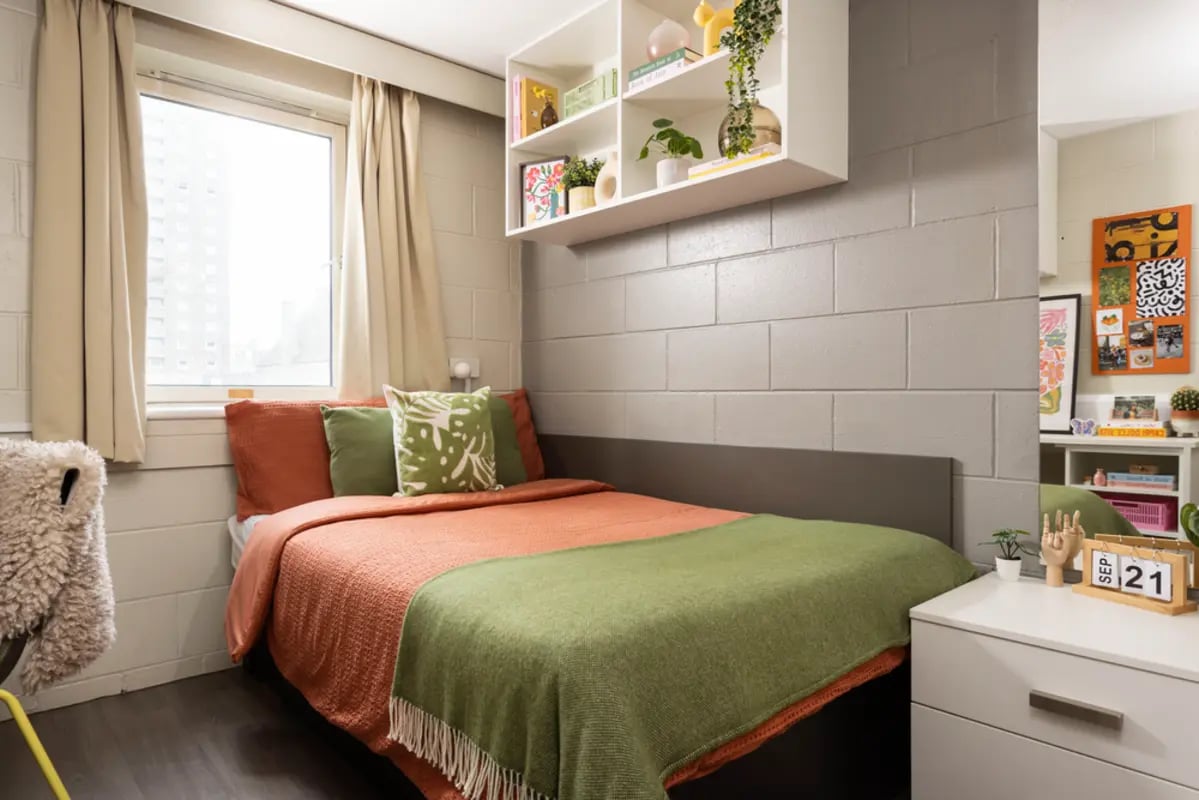 Bed with orange and green blankets on it bedroom at Spring Gardens in Aberdeen Student Accommodation